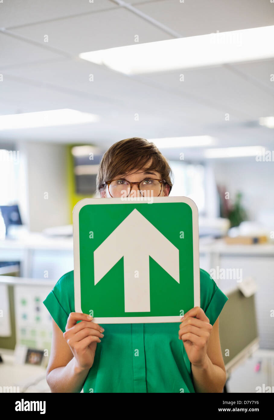 Businesswoman holding arrow sign in office Banque D'Images