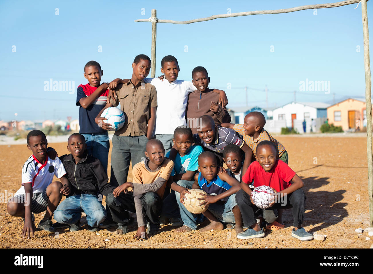 Boys holding soccer balls in dirt field Banque D'Images