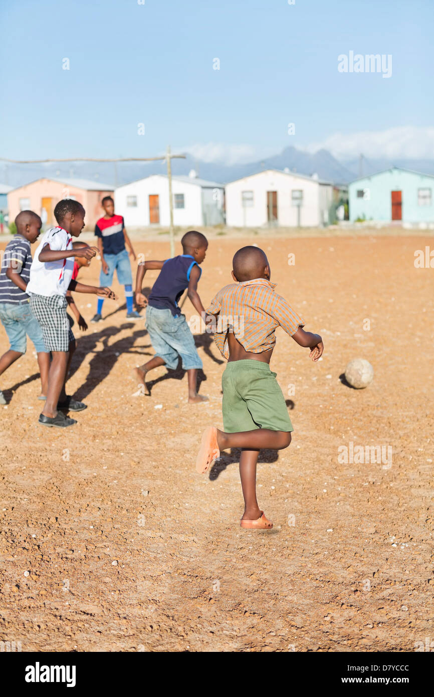 Boys playing soccer together in dirt field Banque D'Images