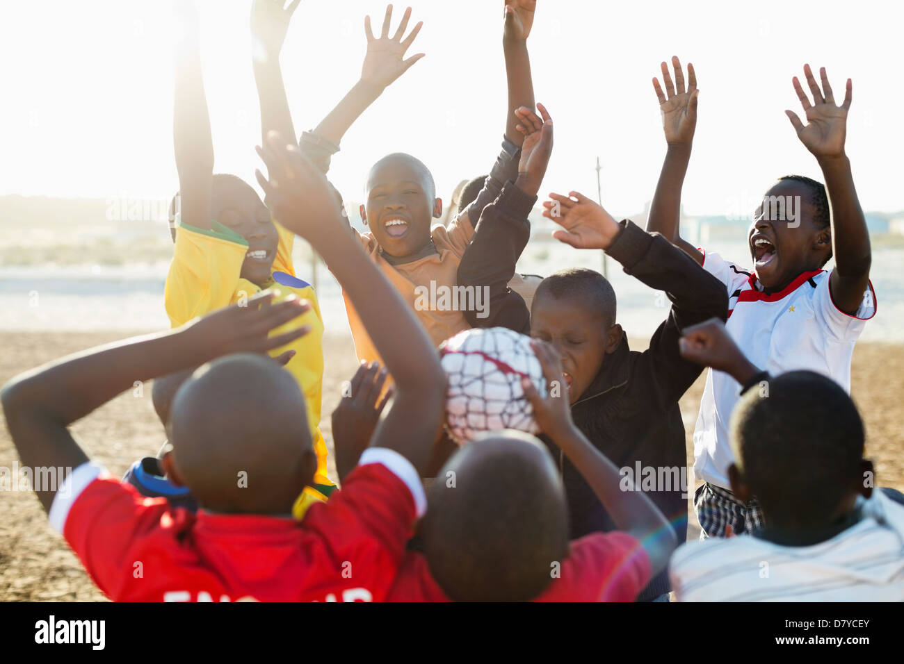 Les garçons cheering together in dirt field Banque D'Images