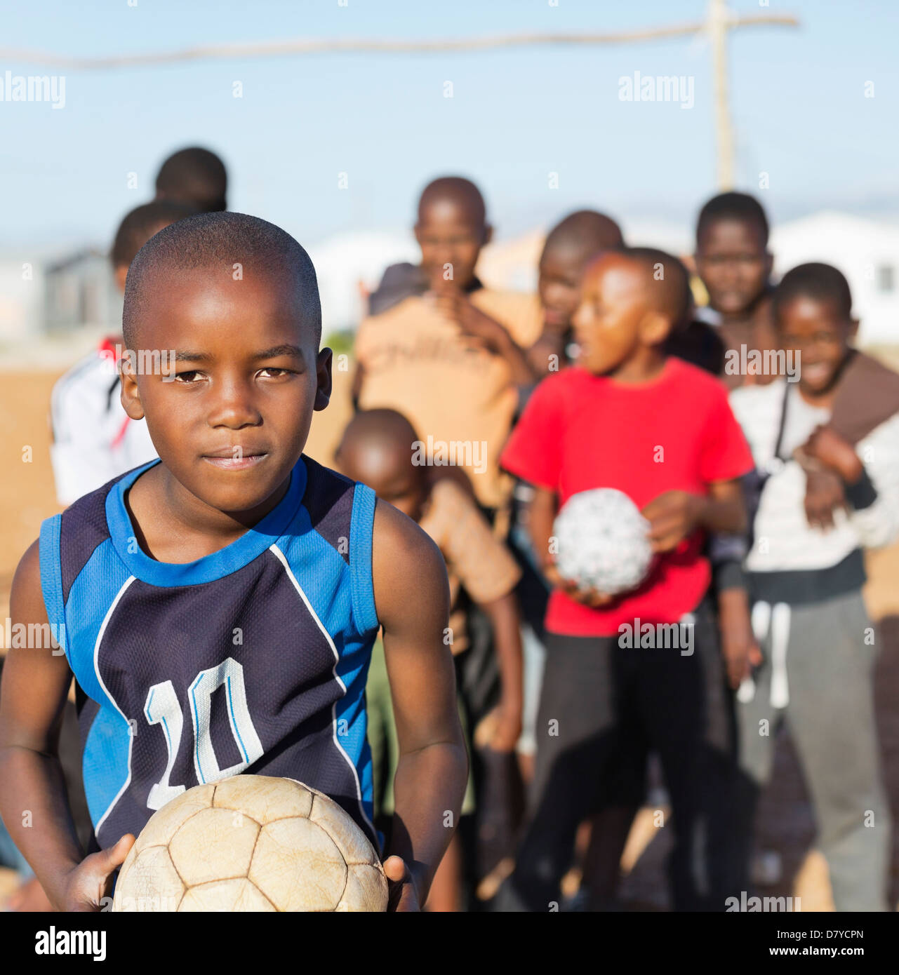 Boys holding soccer balls in dirt field Banque D'Images
