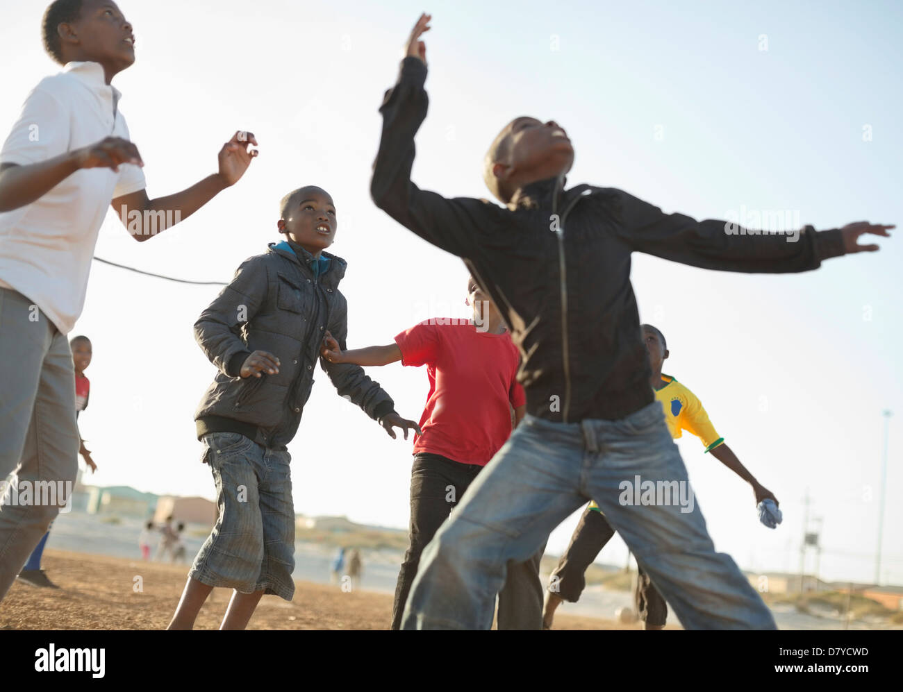 Boys playing soccer together in dirt field Banque D'Images