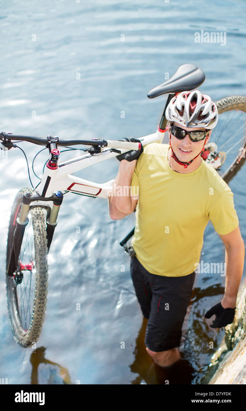 Man carrying mountain bike in river Banque D'Images