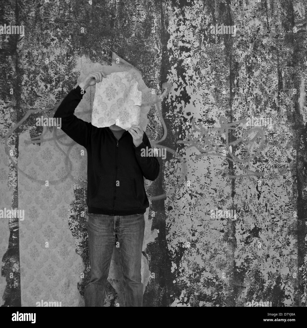Homme avec morceau de papier peint déchiré en décadence. Noir et blanc. Banque D'Images