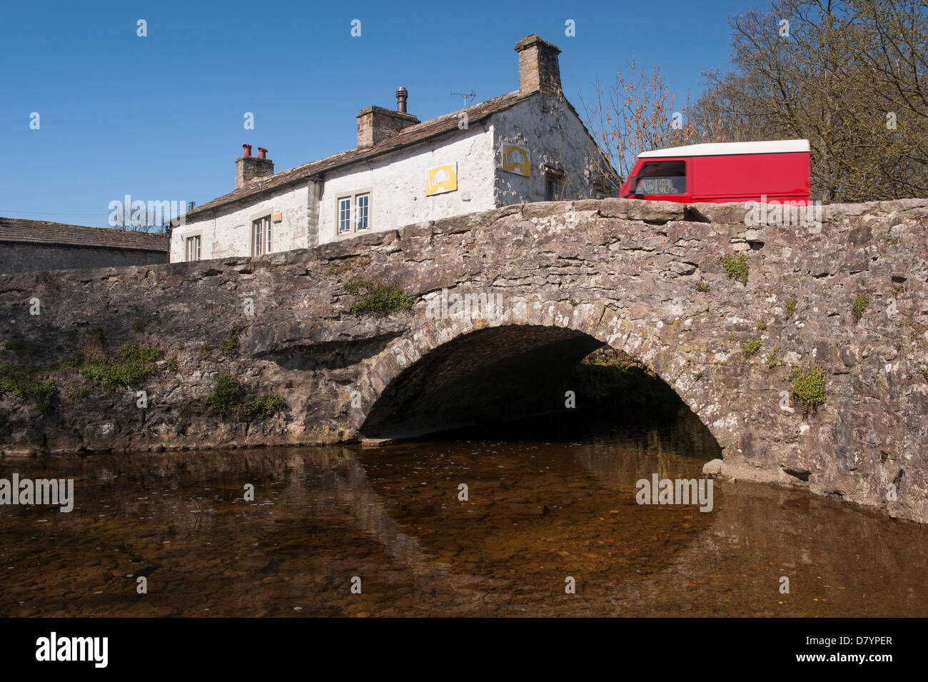 Land Rover Defender sur pierre historique pont à travée unique au-dessus Malham Beck dans le pittoresque village de Dales sur sunny day - Malham, North Yorkshire, England, UK Banque D'Images