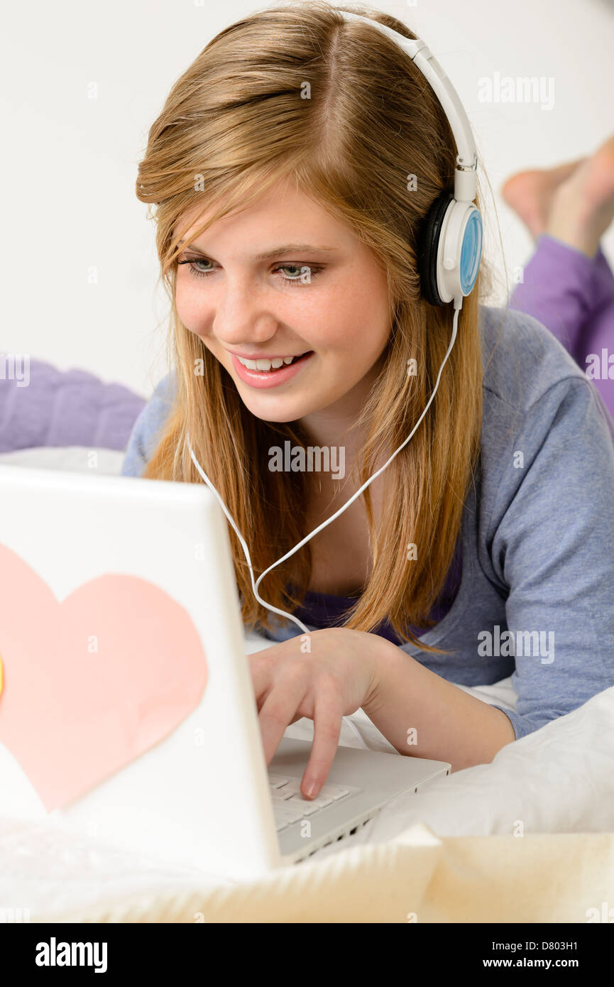 Young woman chatting on laptop et lying on bed Banque D'Images