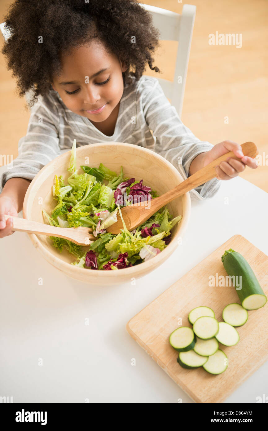 African American girl tossing salad at table Banque D'Images