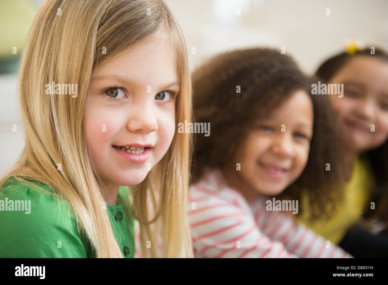 Smiling girls sitting in line Banque D'Images