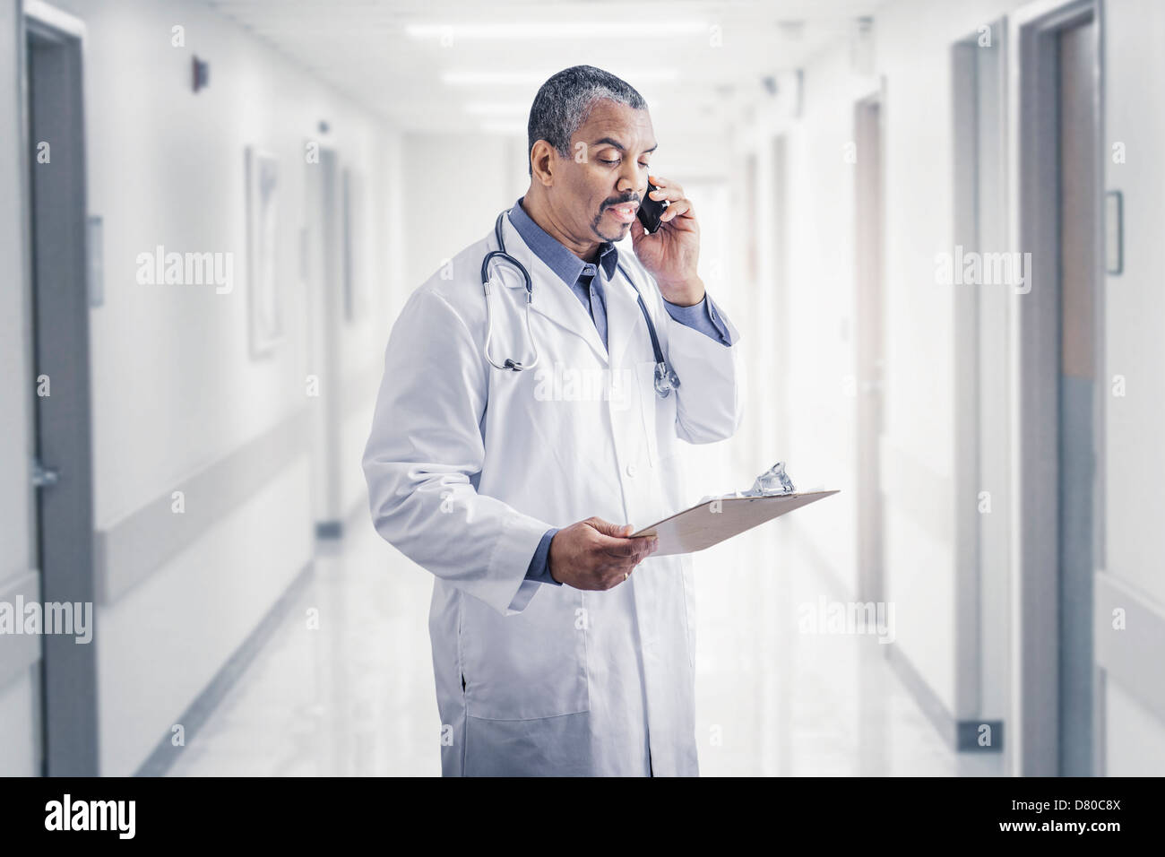 Mixed Race doctor talking on cell phone in hospital Banque D'Images