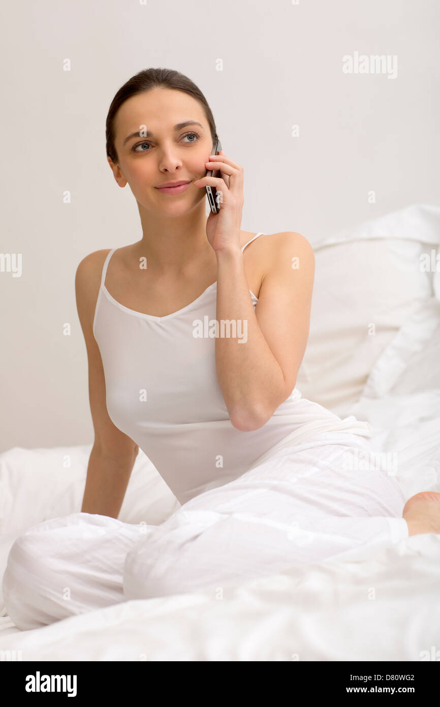 Jeune fille à l'aide de smart phone noir on bed Banque D'Images