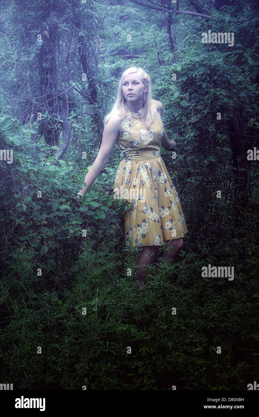 Une fille blonde avec une robe jaune dans les bois Banque D'Images
