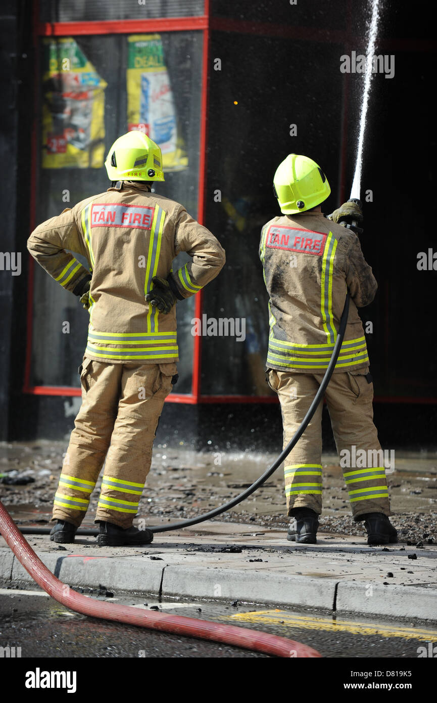 Deux pompiers la lutte contre l'incendie avec un tuyau flexible au Pays de Galles. Banque D'Images