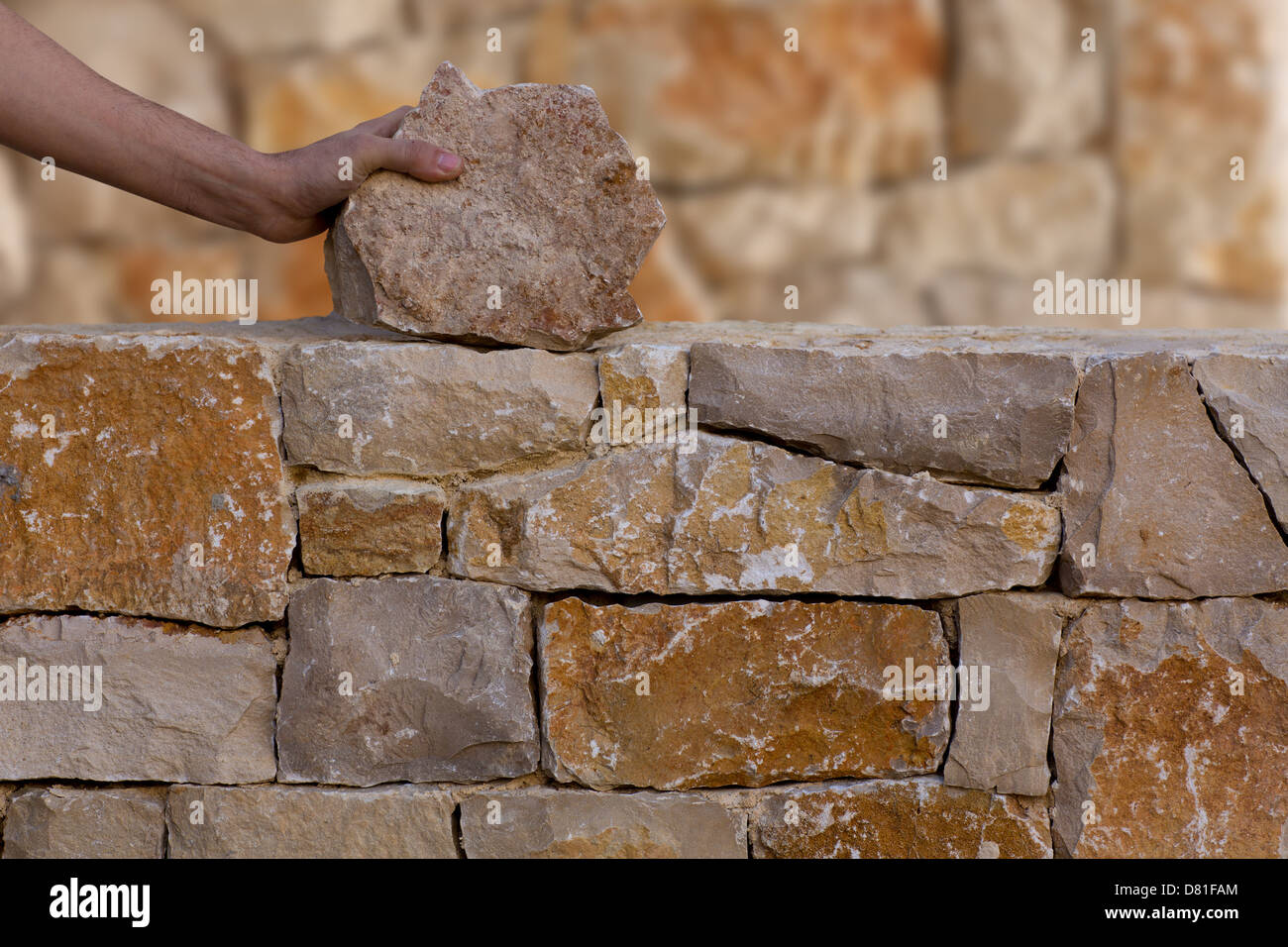 Mason mains travaillant sur mur en pierre de maçonnerie stonewall Banque D'Images