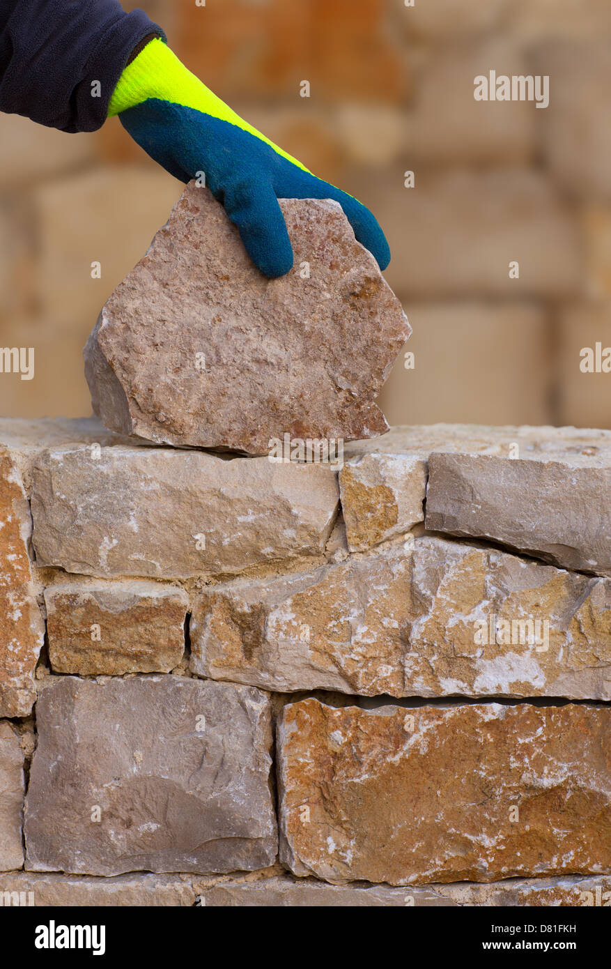 Mason mains travaillant sur mur en pierre de maçonnerie stonewall Banque D'Images