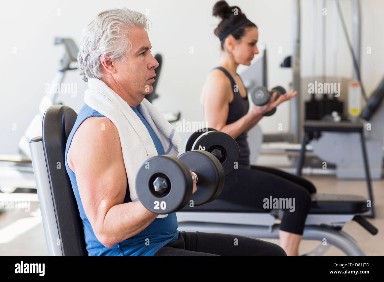 Older Hispanic man lifting weights in gym Banque D'Images