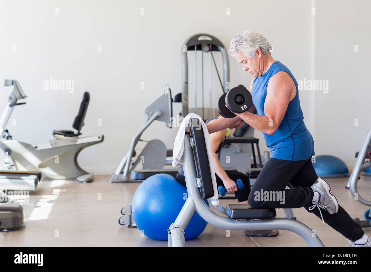 Older Hispanic man lifting weights in gym Banque D'Images