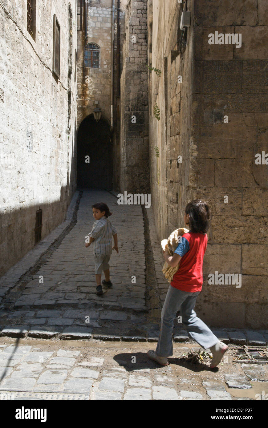 Alep en Syrie. Deux enfants marcher dans une petite vieille rue pavée, dans le vieux centre-ville, site du patrimoine mondial de l'UNESCO. Banque D'Images