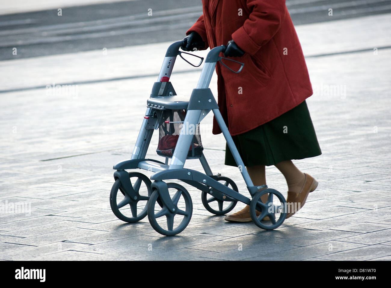 Une vieille femme marche dans la rue avec son déambulateur Banque D'Images