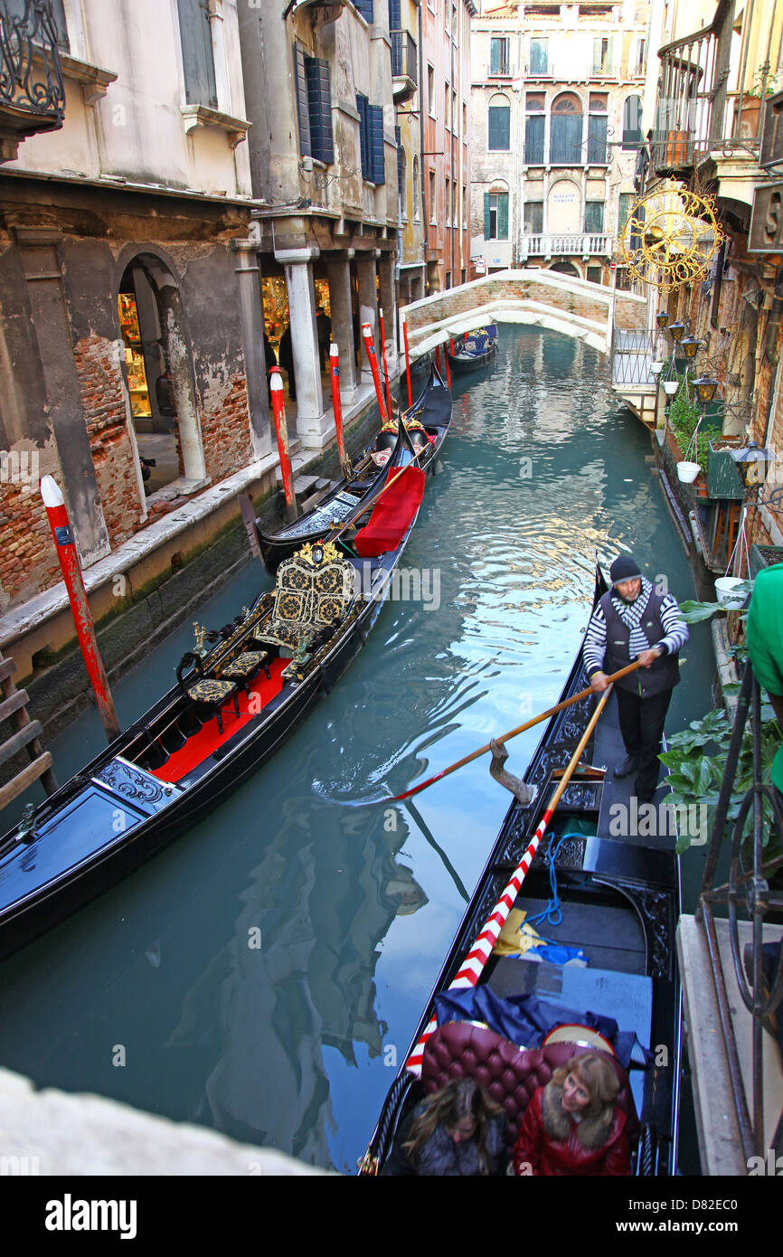 Les gondoles et gondoliers sur un petit canal latéral avec des vieux bâtiments en bois du pont bollards Venise Italie en hiver Banque D'Images