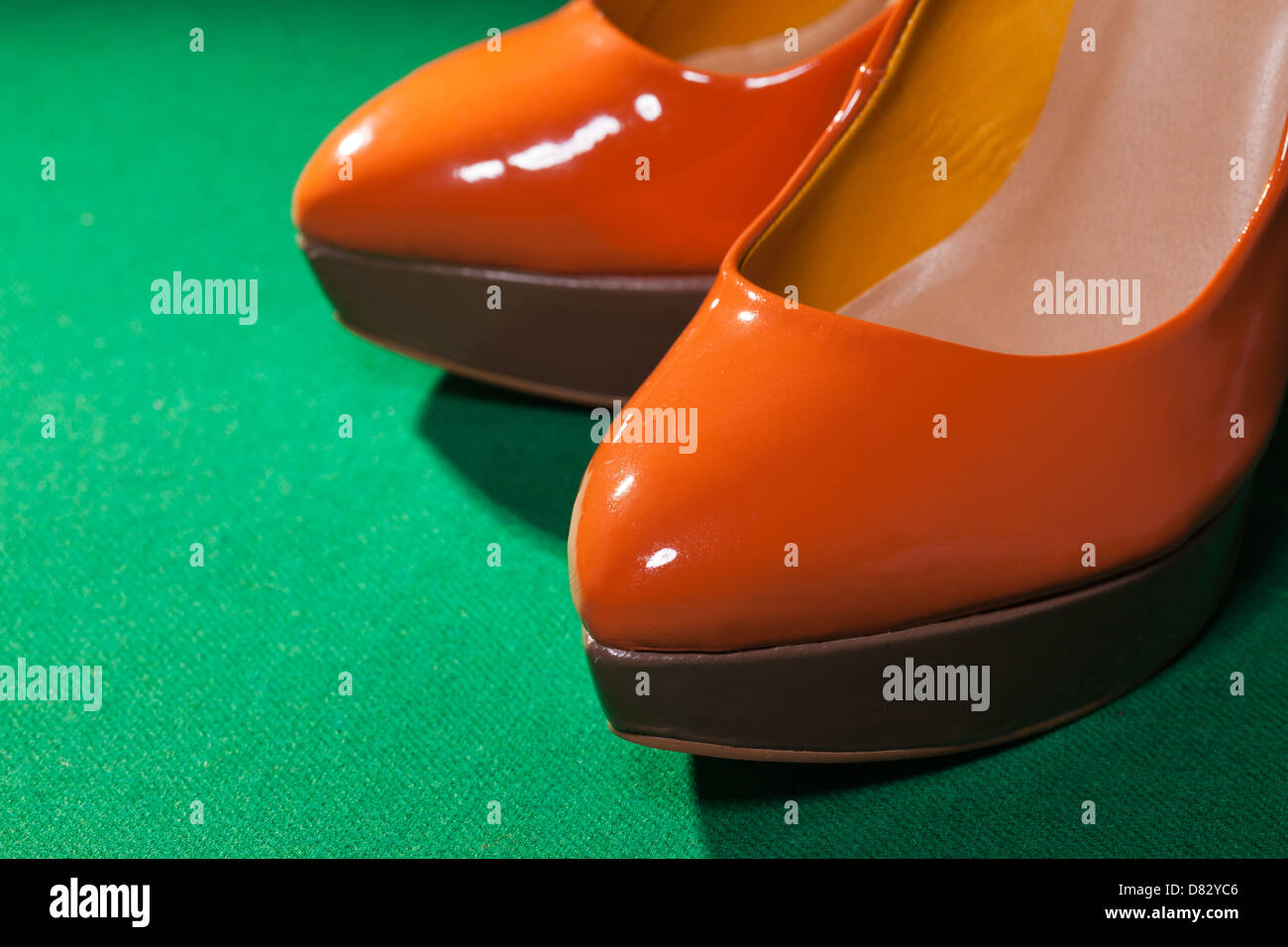 Femme chaussures orange sur fond de tissu vert Banque D'Images