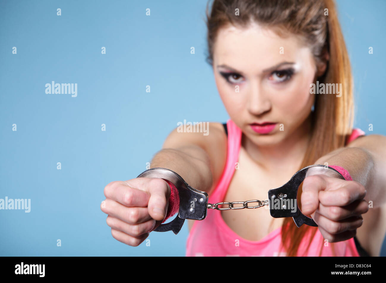 Le crime de l'adolescence - adolescence girl in handcuffs studio shot fond bleu Banque D'Images