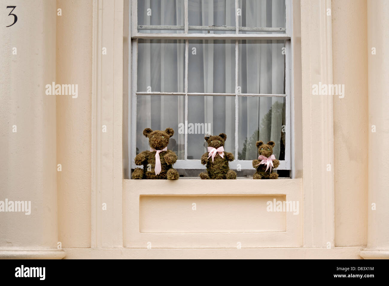 Trois ours en peluche assis sur un rebord de fenêtre Banque D'Images