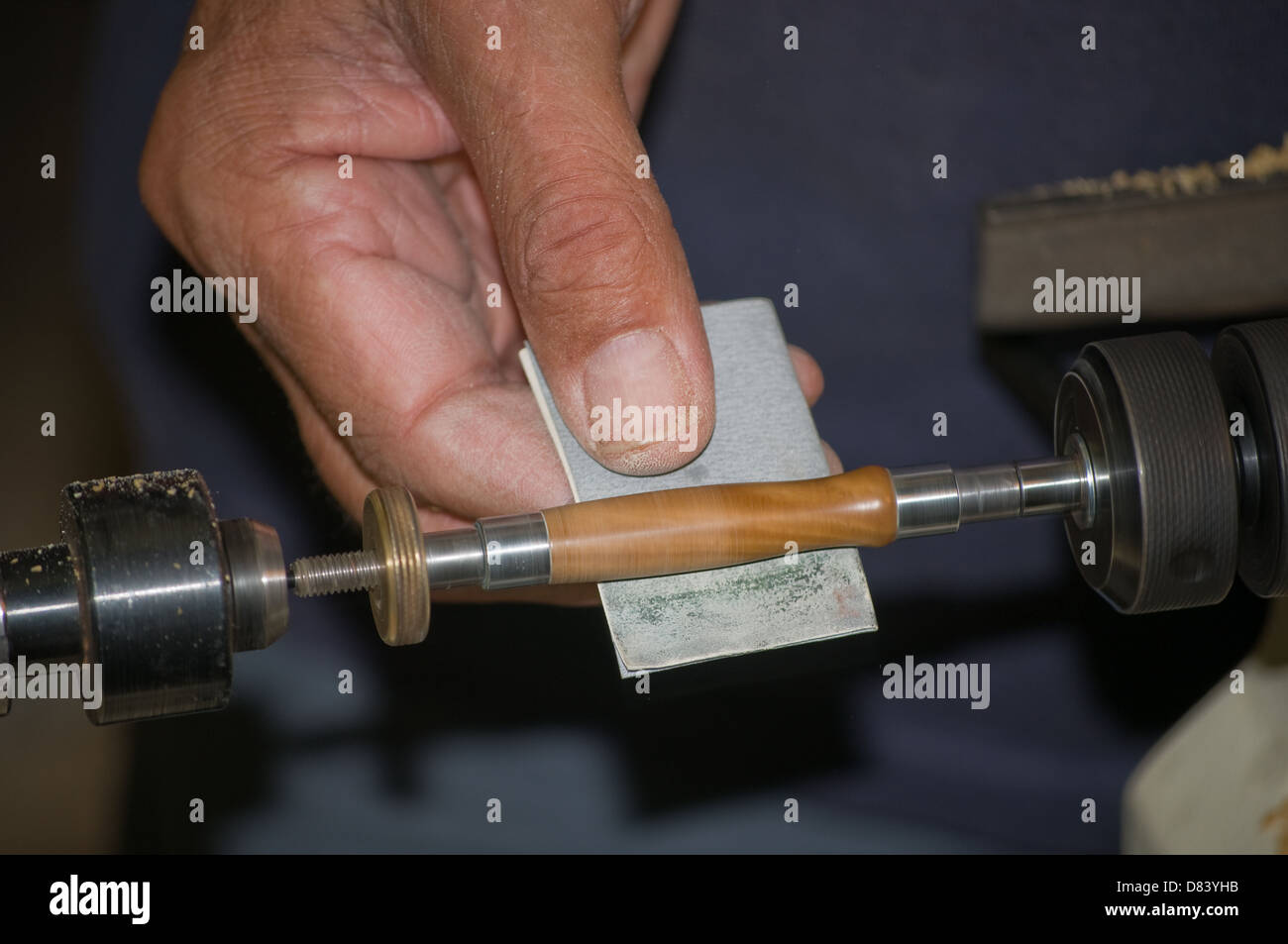 En utilisant du papier de verre extra fin sur un tour pour terminer poncer un stylo en bois Banque D'Images