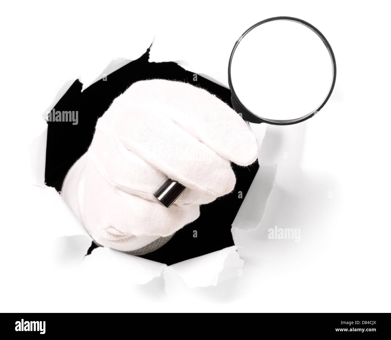 L'homme avec des gants est holding magnifying glass à travers un trou dans du papier blanc Banque D'Images