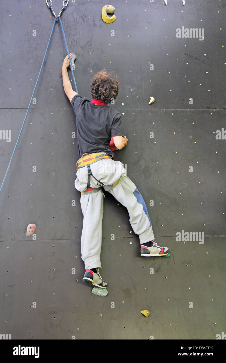 Jeune grimpeur sur un mur artificiel, aller en haut Banque D'Images