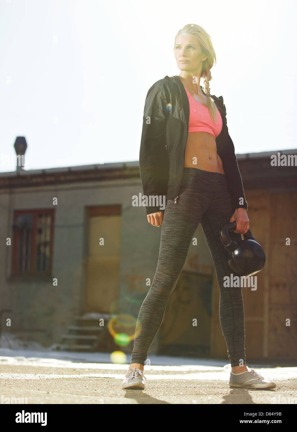 Dans les vêtements de sport femme crossfit attrayant tenant une kettlebell outdoors Banque D'Images