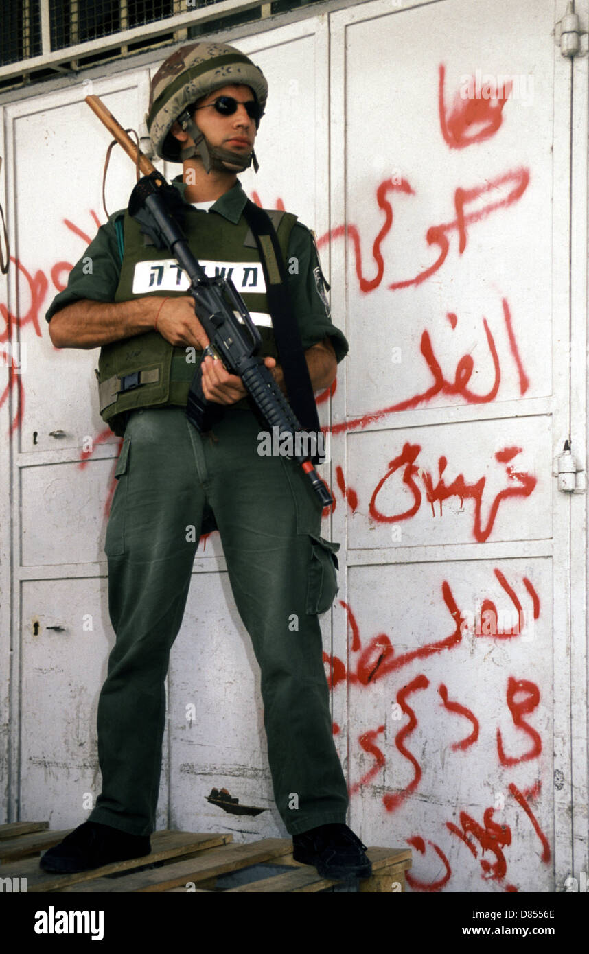 Un soldat israélien armé avec M16 mitrailleuses tient une garde devant un magasin palestinien pulvérisé de graffiti anti-israélien en arabe dans la vieille ville du quartier musulman Jérusalem-est Israël Banque D'Images