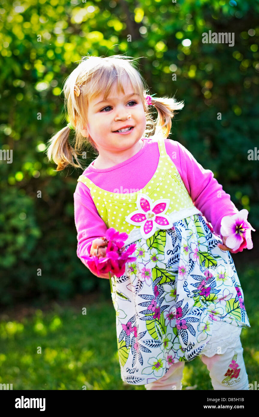 Petite fille danse tout-petits avec des fleurs dans les mains Banque D'Images