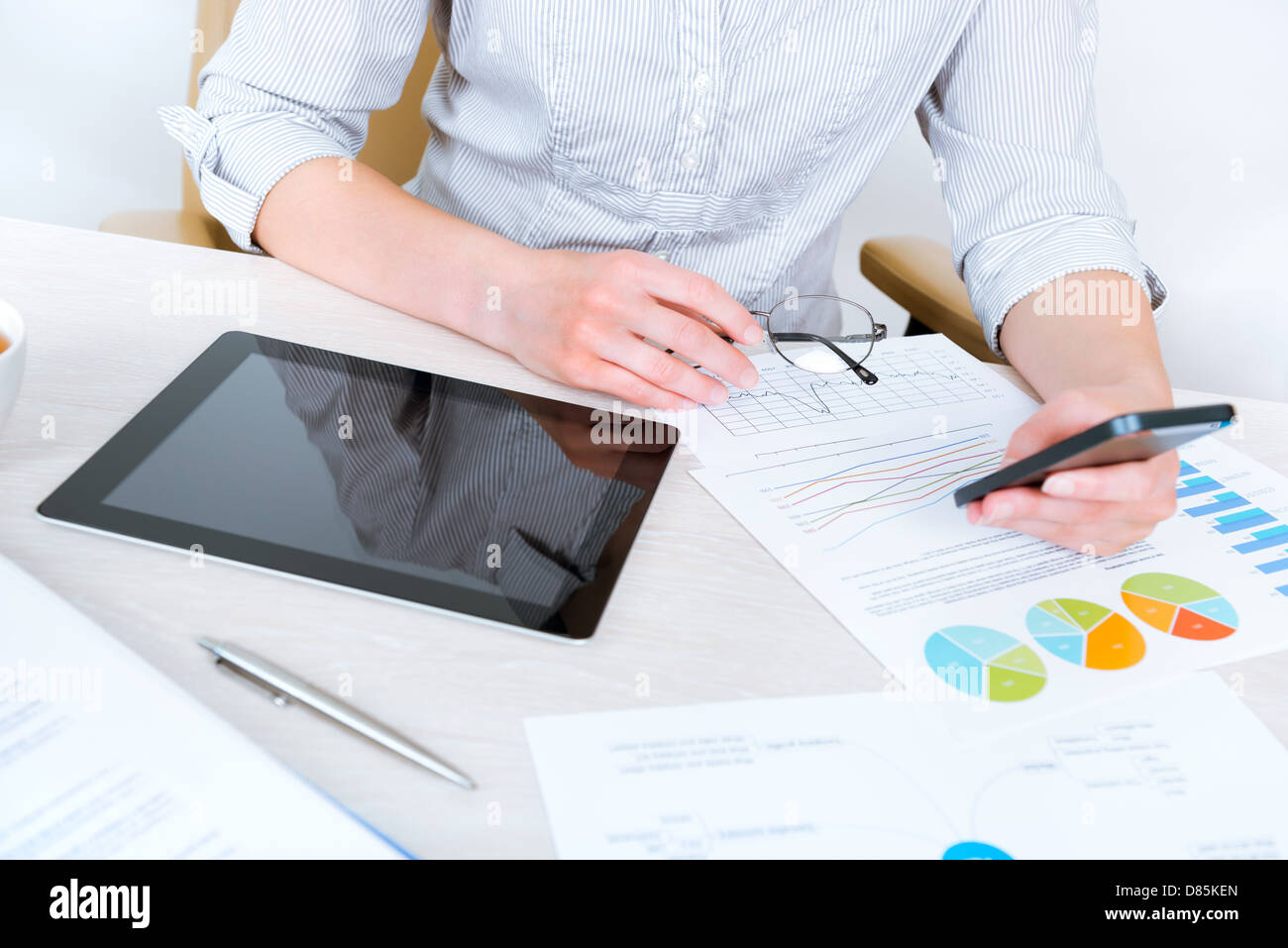 Young businesswoman sitting at desk réussie au bureau et à l'aide de téléphone mobile pour la communication d'entreprise Banque D'Images