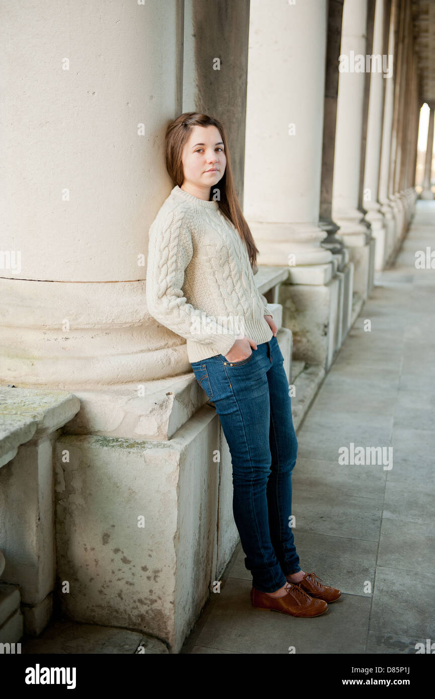 Teenage girl in cavalier laineux appuyé contre la colonne d'un bâtiment ancien. Banque D'Images