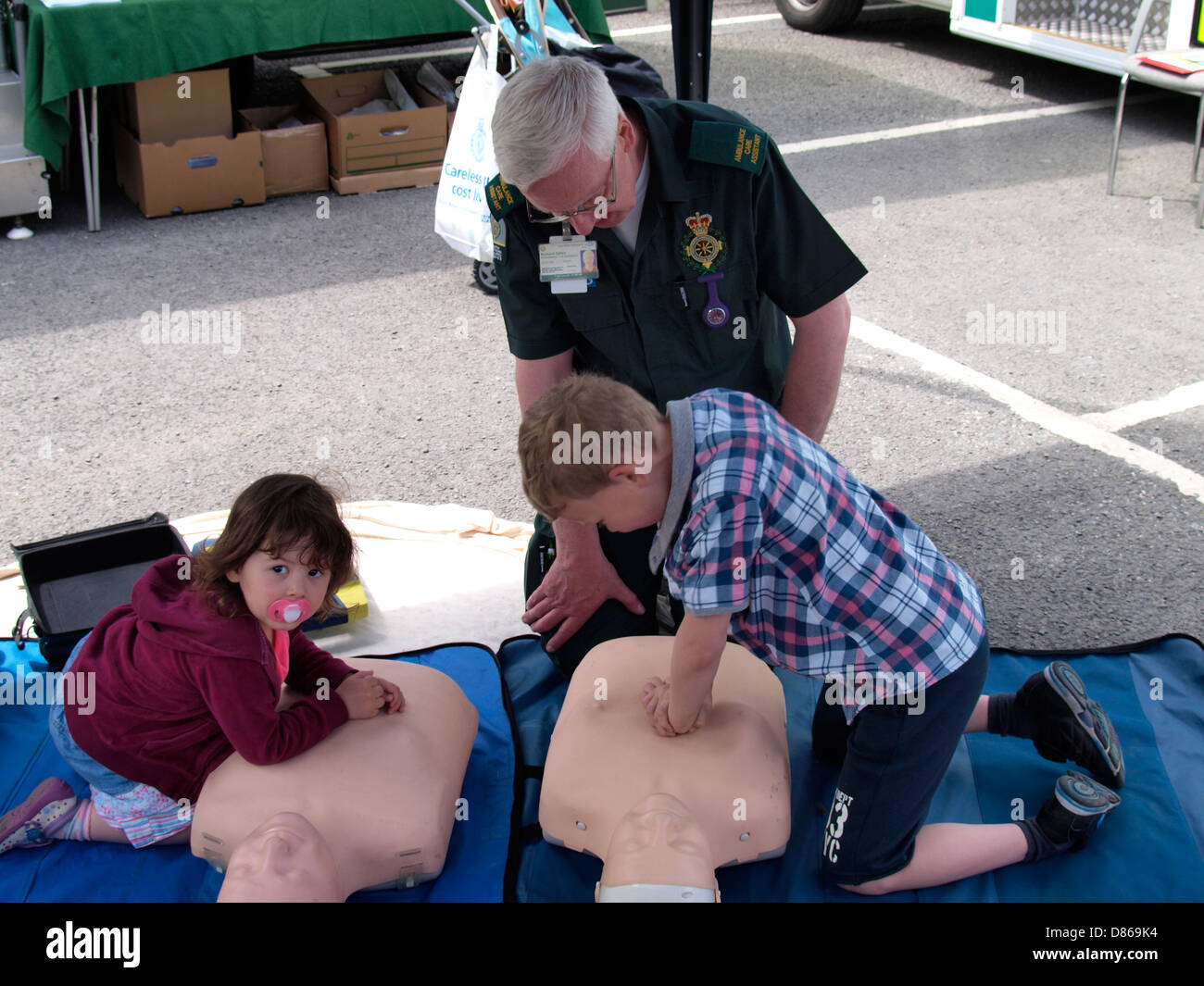 Richard Oaten de l'Ambulance avec quelques jeunes enfants faire la RCR sur une pratique mannequin, Barnstaple, Devon, UK 2013 Banque D'Images