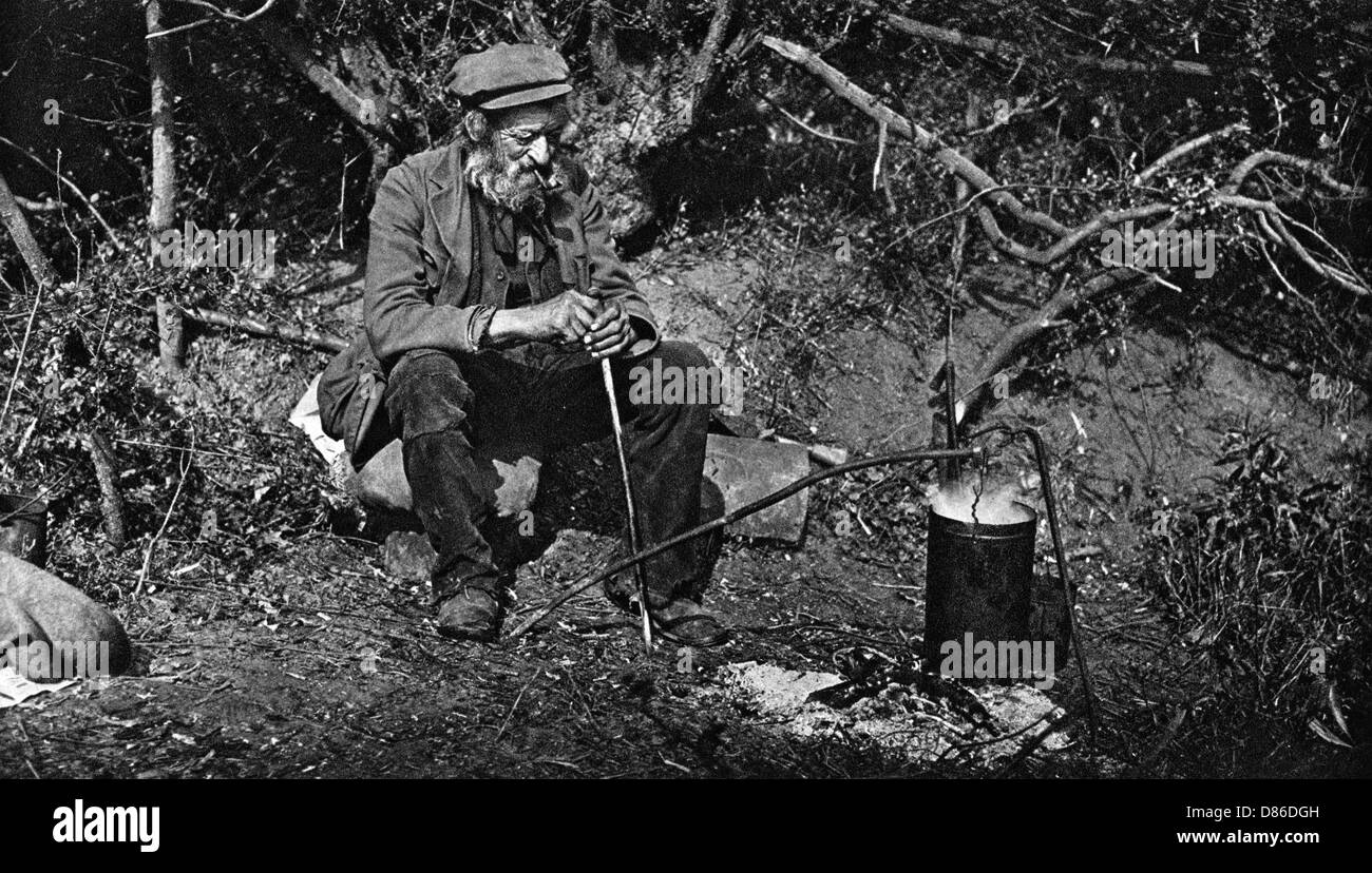 Un clochard assis près d'un feu Banque D'Images