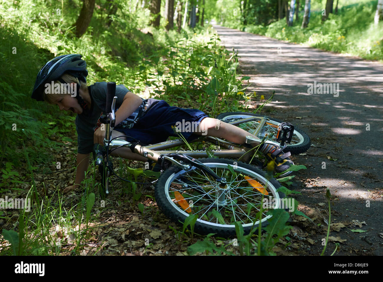 Garçon blond enfant 6 - 7 ans équitation vélo avec casque de vélo en été, comme un accident, blessés, automne Banque D'Images