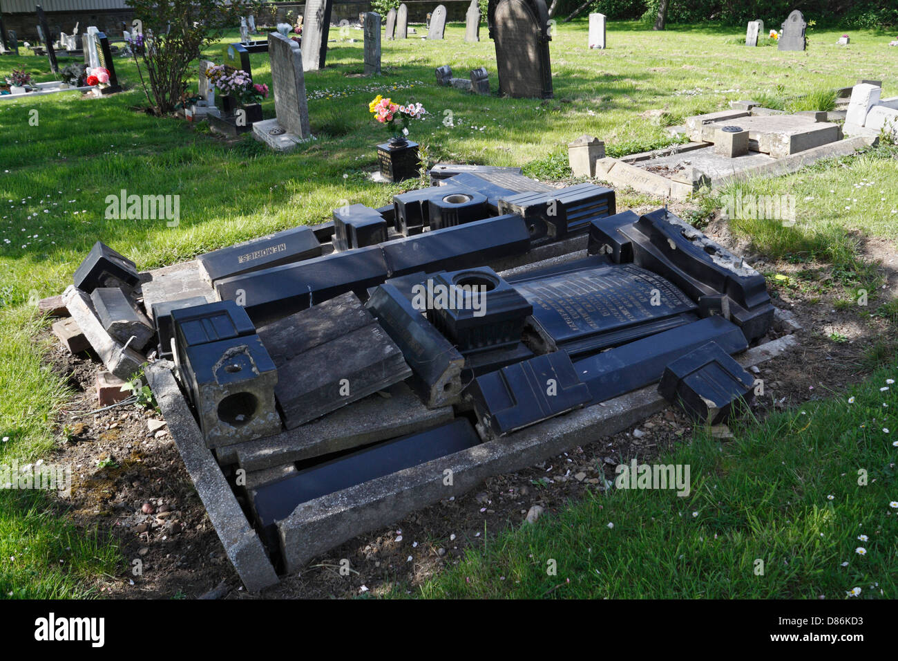 Une pierre tombale démantelée et non gardée, un cimetière avec les pierres commémoratives empilées endommagées Banque D'Images