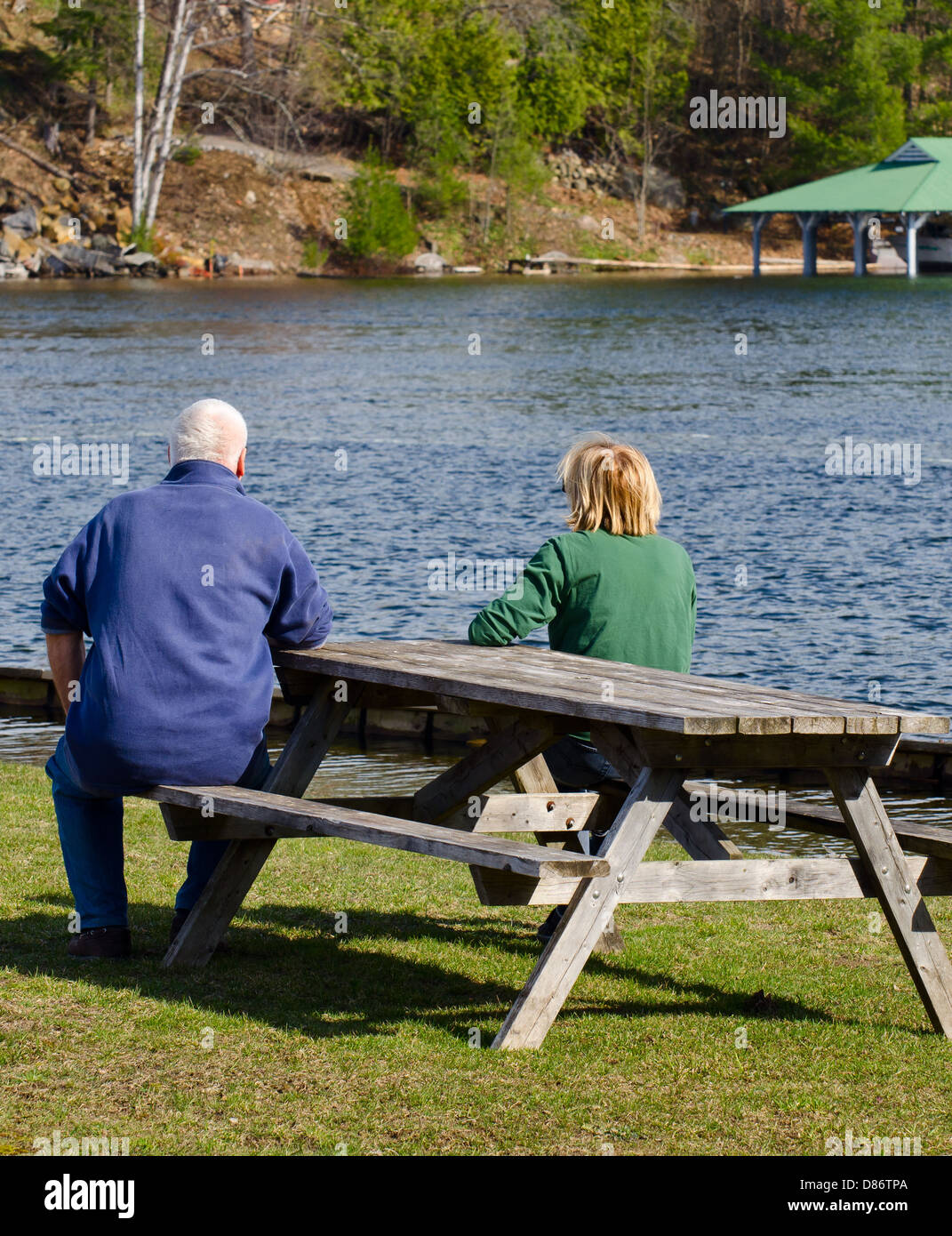Couple assis sur un banc au bord d'un lac Banque D'Images