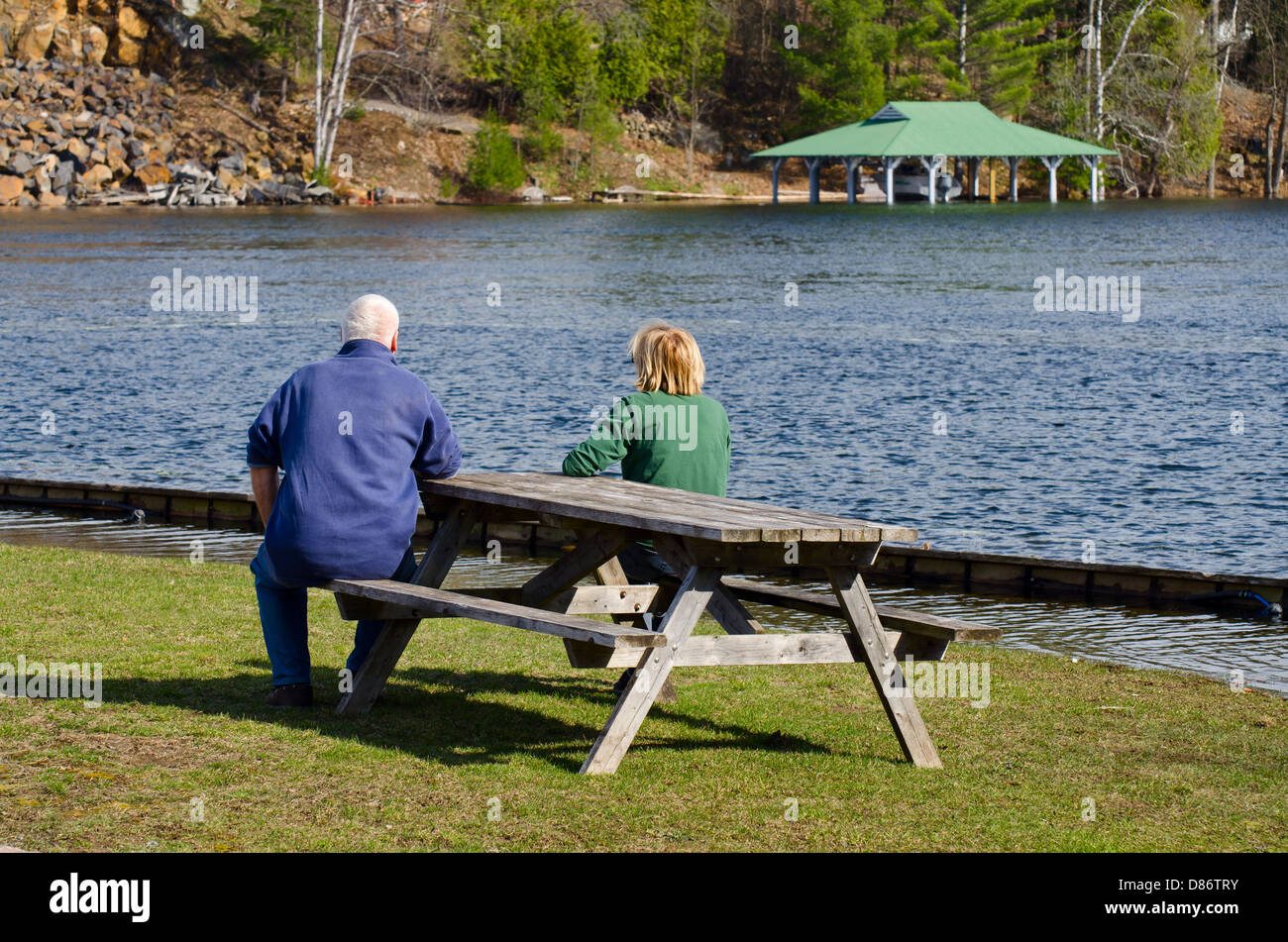 Couple assis sur un banc au bord d'un lac Banque D'Images