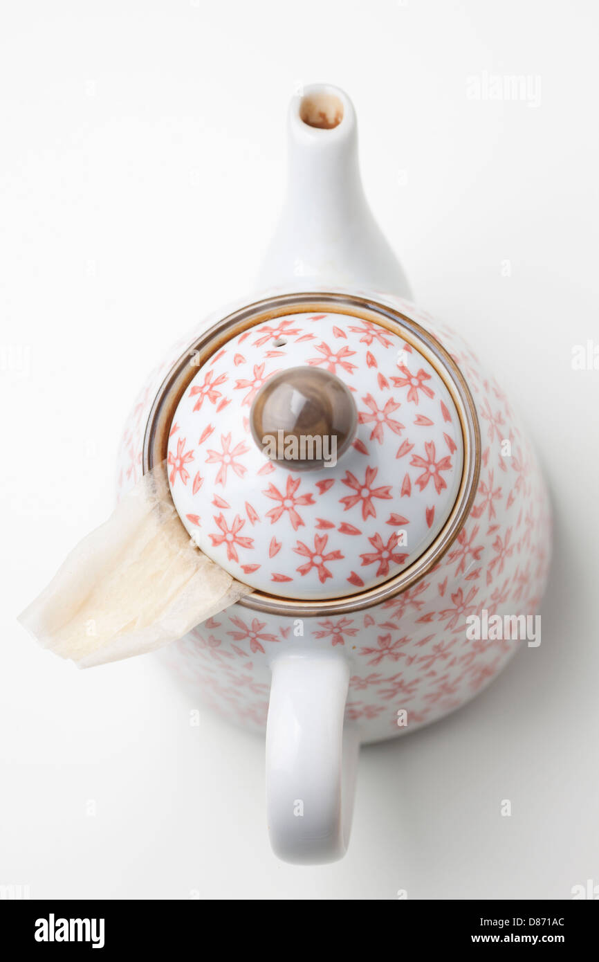 Pot de thé japonais avec motif floral et sachet de thé sur fond blanc Banque D'Images
