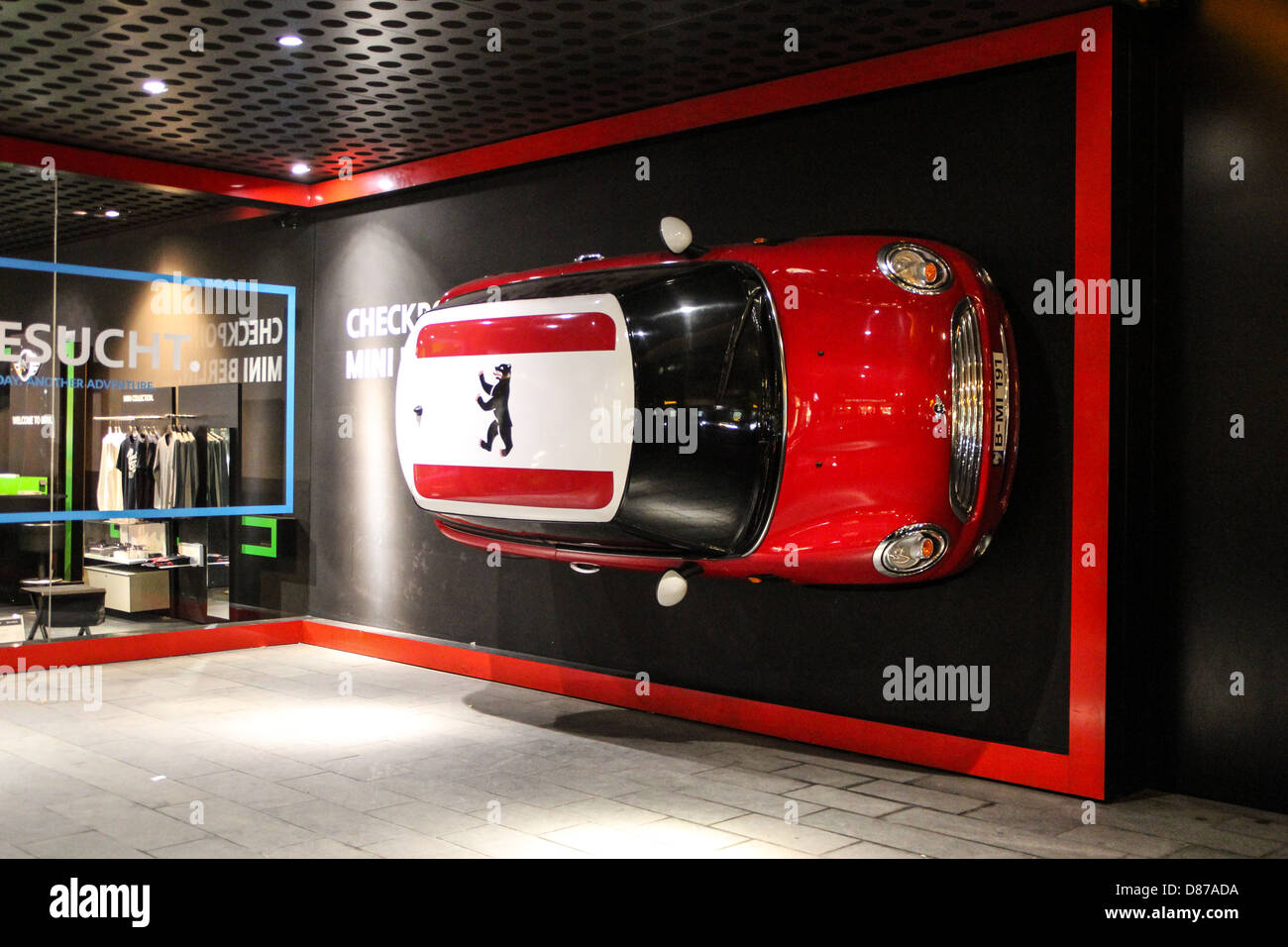 BMW Mini une voiture rouge fixé au mur, avec un ours de Berlin logo emblème du drapeau sur le toit, dans la Friedrichstrasse, Berlin, Allemagne Banque D'Images