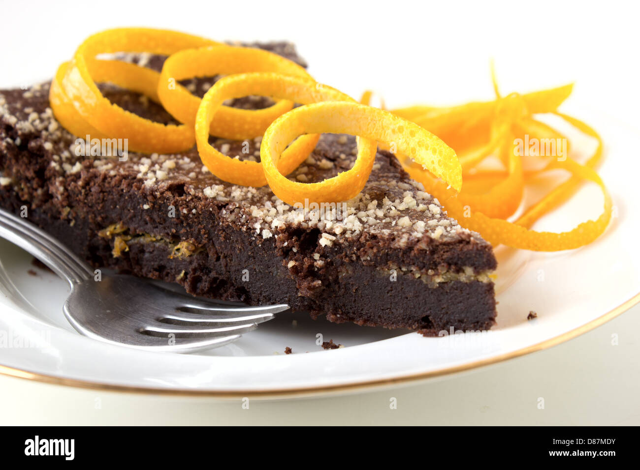 Gâteau au chocolat avec couche orange sur plaque blanche décorée de zeste d'orange. Banque D'Images