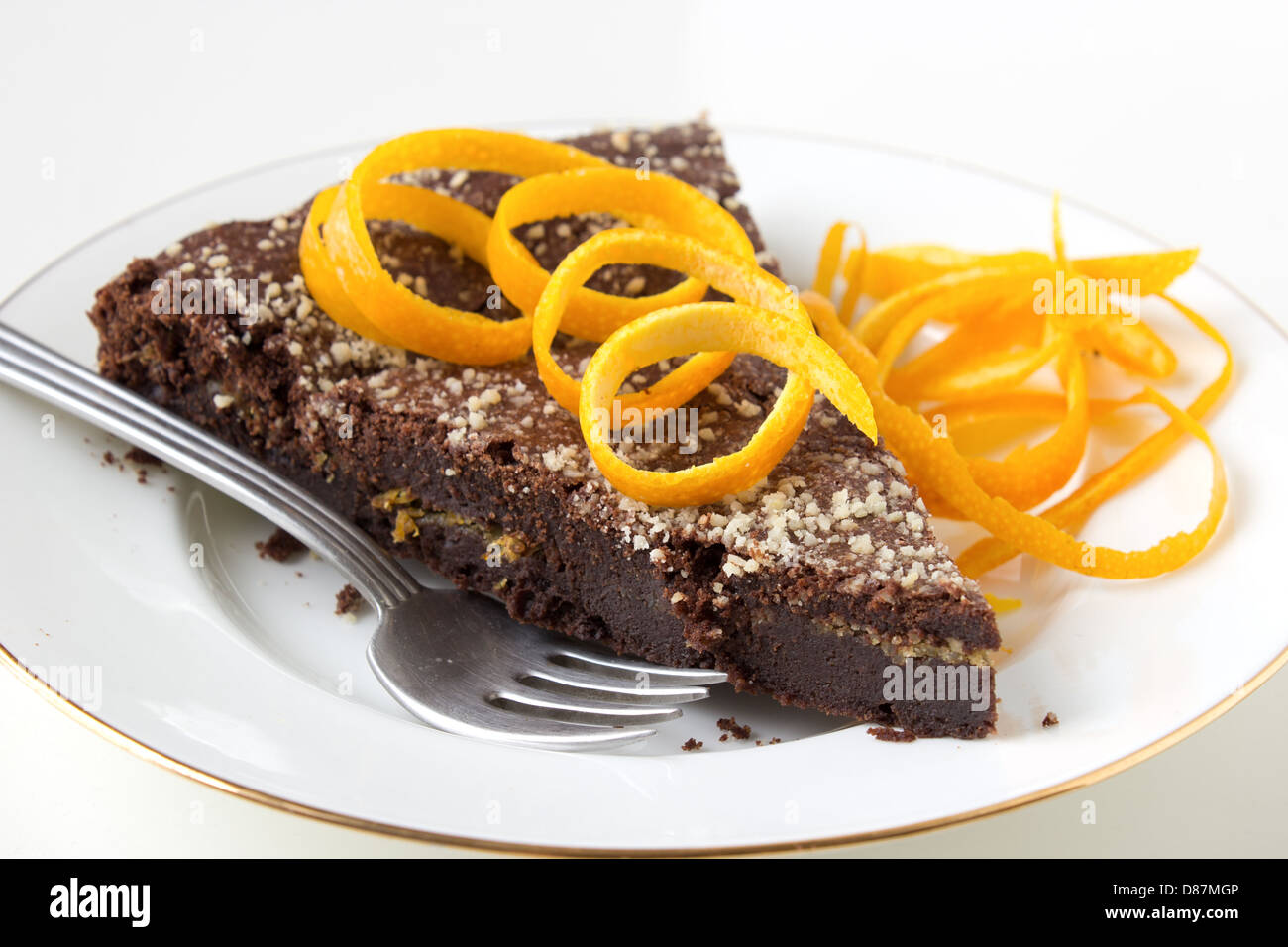 Gâteau au chocolat avec couche orange sur plaque blanche décorée de zeste d'orange. Banque D'Images