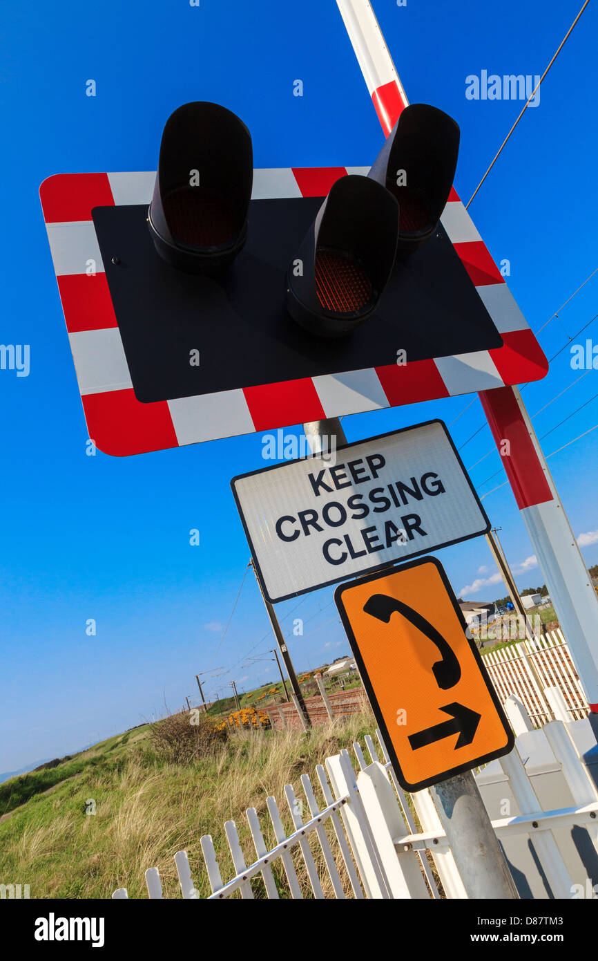 Des panneaux d'avertissement. feux de circulation et d'urgence téléphone à côté d'un passage à niveau, près d'Irvine, Ayrshire, Scotland Banque D'Images