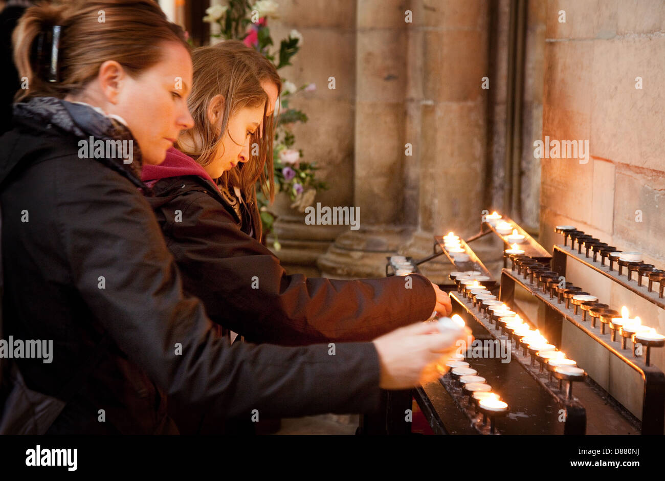 Adolescentes adolescents adolescents bougies d'éclairage d'une bougie à l'intérieur de la cathédrale York Minster, Yorkshire UK Banque D'Images
