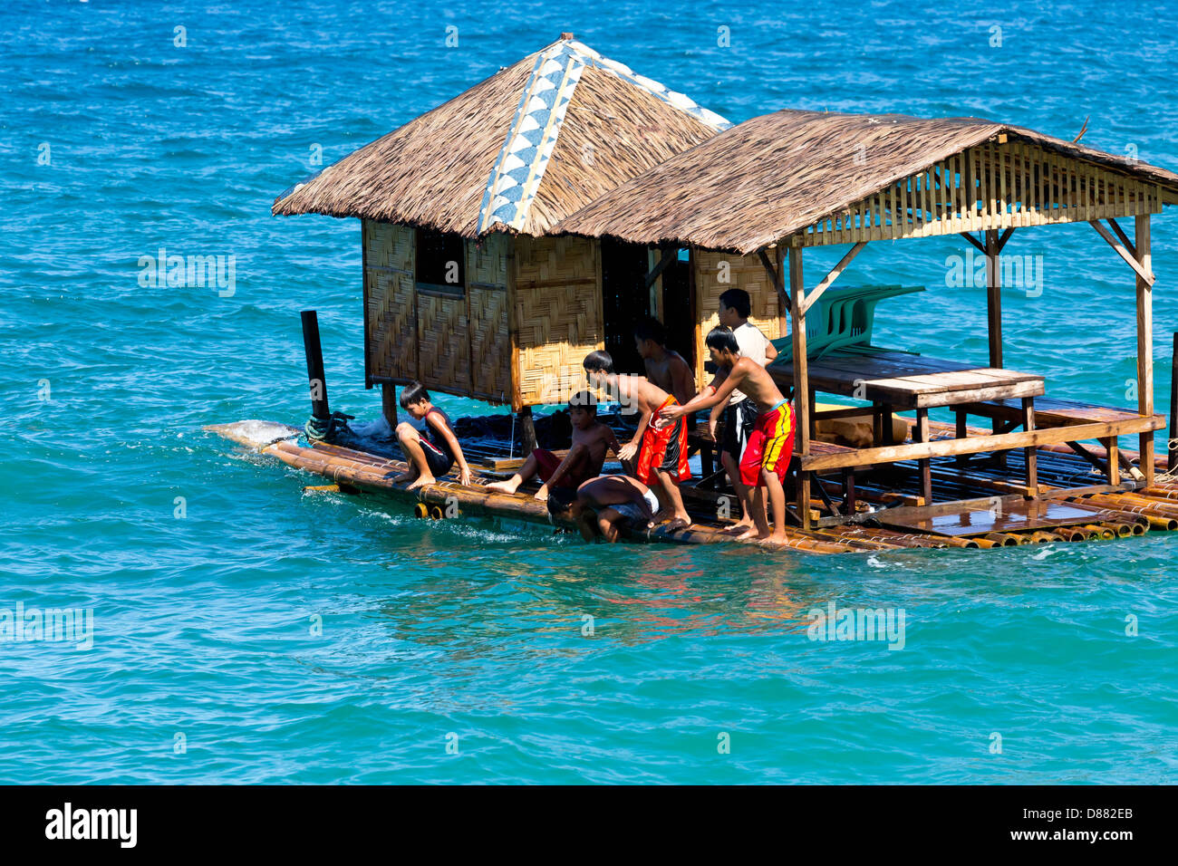 Les enfants d'un saut d'une maison flottante dans l'océan sur l'île de Mindoro, Philippines Banque D'Images