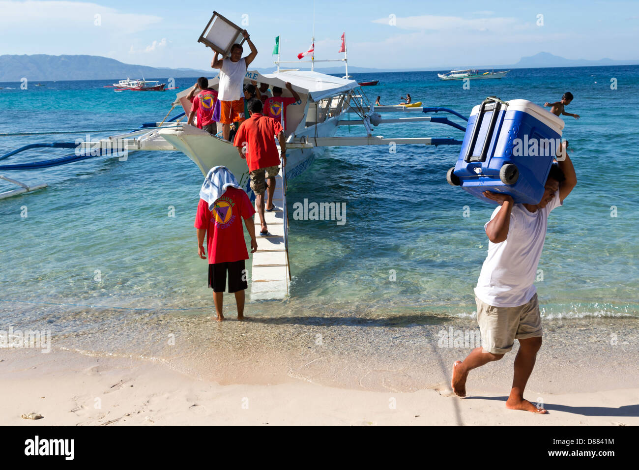Le déchargement d'un bateau typique sur le grand La Laguna Beach sur l'île de Mindoro, Philippines Banque D'Images