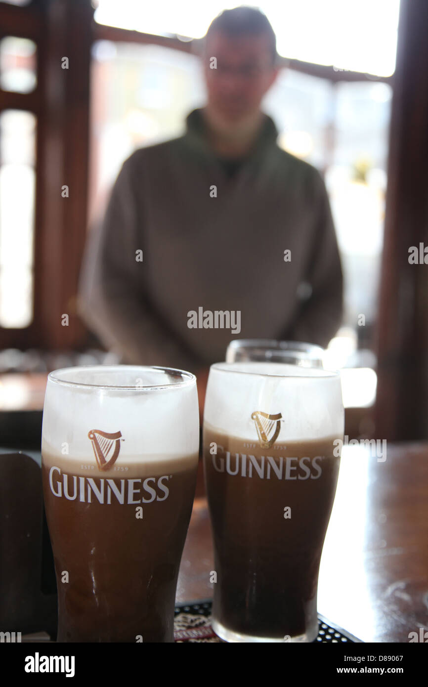 Un homme attend que ses pintes de Guinness à être versé à un pub Banque D'Images