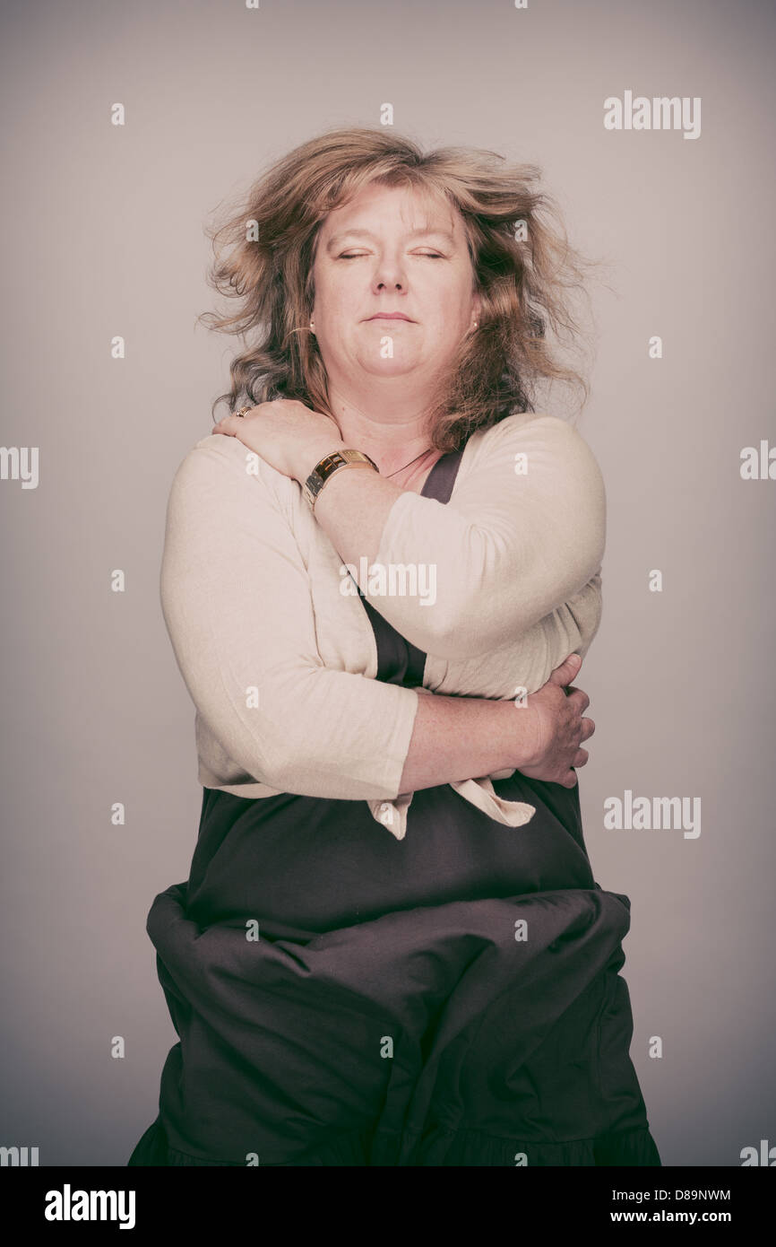 Middle-aged woman saute joyeusement avec ses yeux fermés. Banque D'Images